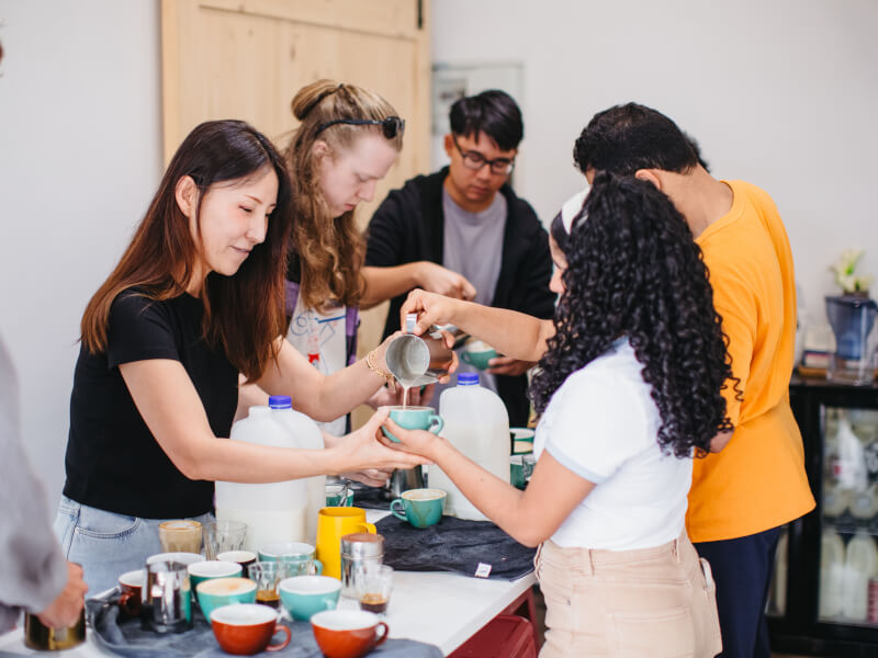 Woman pouring milk into latte cup at barista class 